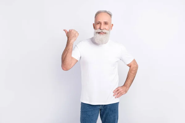 Photo of cheerful grey hair beard old man point empty space wear white t-shirt jeans isolated on grey color background — Stock Photo, Image