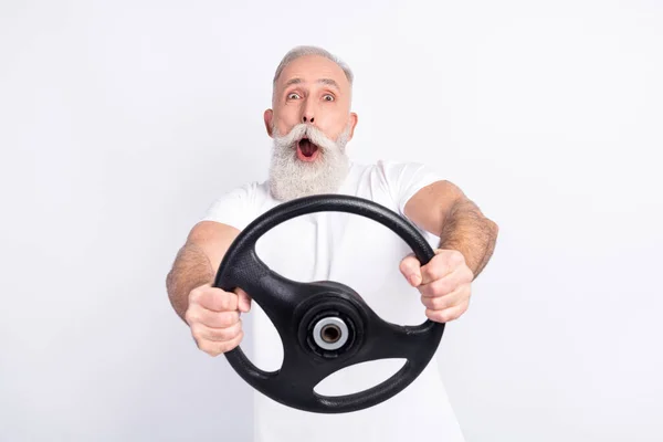 Retrato de atraente alegre engraçado homem segurando em mãos volante equitação se divertindo isolado sobre luz cinza cor fundo — Fotografia de Stock