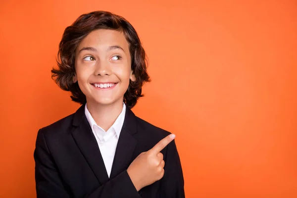 Photo of young charming dreamy happy positive boy look point finger empty space news isolated on orange color background —  Fotos de Stock