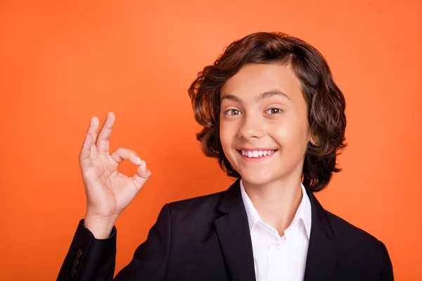 Foto de feliz positivo encantador menino fazer dedo ok sinal recomendo isolado no fundo cor de laranja — Fotografia de Stock