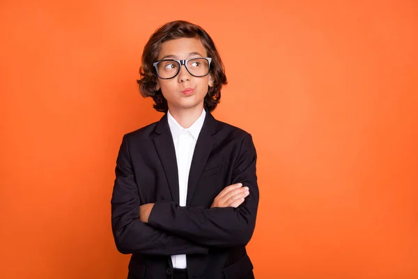 Photo of young minded boy look empty space wear glasses arms folded isolated on orange color background —  Fotos de Stock