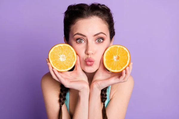 Photo portrait of young woman keeping two fresh oranges sending air kiss isolated on pastel purple color background — Foto Stock