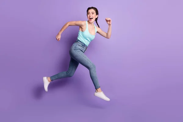 Full body profile photo of cheerful lady run look back wear top jeans isolated on purple color background —  Fotos de Stock