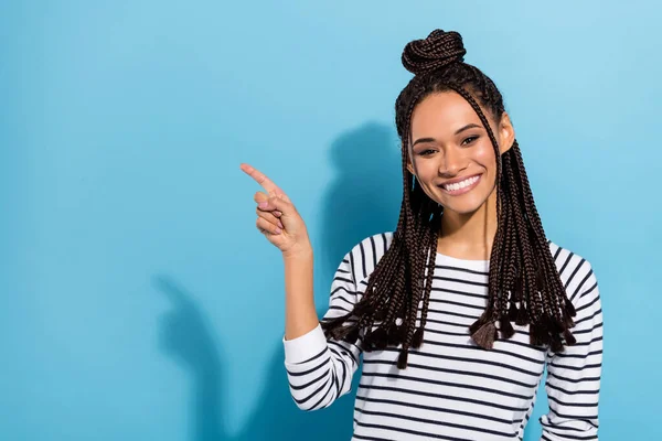 Photo portrait of smiling girl with dreadlocks showing empty space with finger smiling isolated pastel blue color background — Foto Stock