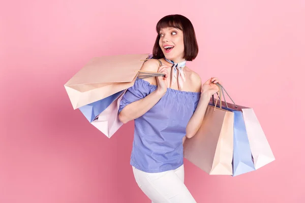 Фотопортрет жінки, яка ходить по магазинах у вихідні дні, тримаючи сумки, які виглядають копійками, ізольовані на пастельному рожевому кольоровому фоні — стокове фото