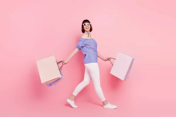 Full längd kropp storlek sida profil foto kvinna går på shopping med paket isolerad pastell rosa färg bakgrund — Stockfoto