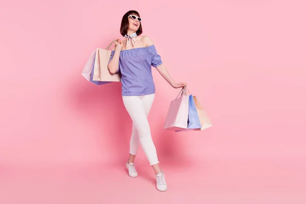 Full length body size photo woman with packages walking in shopping mall overjoyed dreamy isolated pastel pink color background — Fotografia de Stock