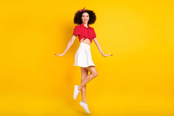 Повний розмір профілю фотографія крутої оптимістичної брюнетки стрибок волосся леді носити червону спідницю верхньої смуги ізольовані на жовтому кольоровому фоні — стокове фото