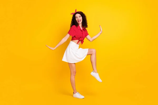 Teljes méretű fotó aranyos optimista barna haj hölgy tánc viselet piros felső szoknya elszigetelt sárga színű háttér — Stock Fotó