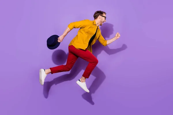Full storlek profil sida foto av glada galen ung man hoppa upp köra tomt utrymme isolerad på violett färg bakgrund — Stockfoto