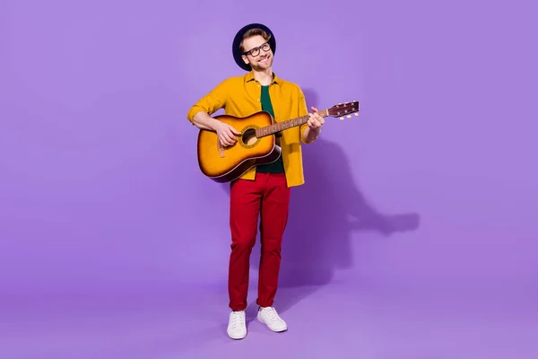 Full body foto van creatieve vrolijke positieve jongeman kijken lege ruimte spelen gitaar geïsoleerd op violette kleur achtergrond — Stockfoto