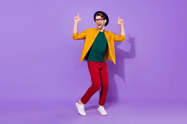 Full size photo of attractive young funky man point fingers look empty space good mood dance isolated on violet color background — ストック写真