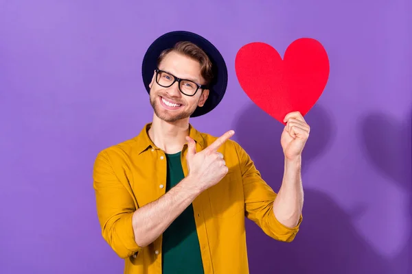 Foto do jovem feliz sorriso positivo ponto dedo cartão de papel conselho adverise coração sugerem isolado sobre fundo cor violeta — Fotografia de Stock