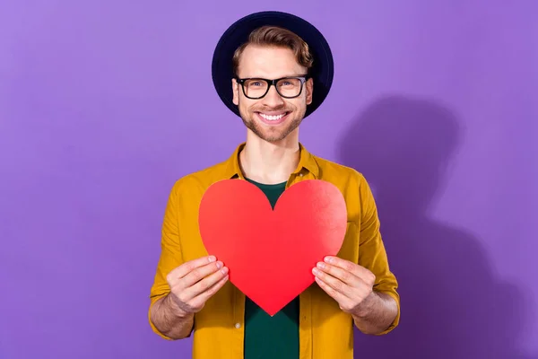 행복 한 미소를 짓고 있는 젊은 남자의 사진은 보라색 배경 위에 고립된 커다란 빨간 종이 심장 사랑을 담고 있다 — 스톡 사진