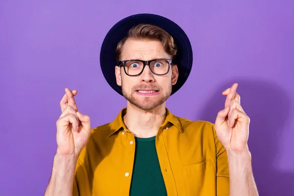 Fénykép a fiatal férfi boldogtalan ideges ideges aggódó keresztbe ujjak remény kívánság szerencse elszigetelt felett lila színű háttér — Stock Fotó