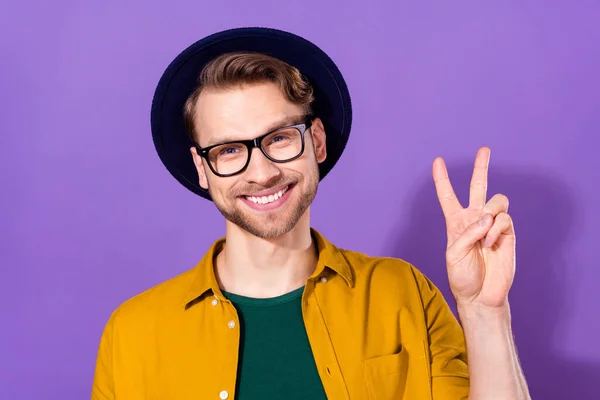 Фото прохладно веселый очаровательный молодой человек хорошее настроение показать V-знак улыбку изолированы на фиолетовом фоне цвета — стоковое фото