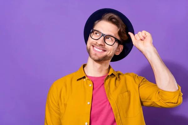 Photo de jeune bel homme heureux sourire positif main toucher chapeau rêve regarder vide espace isolé sur fond de couleur violette — Photo