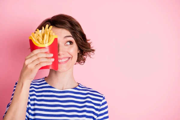 Retrato de jovem bonita sorridente menina alegre olhar copyspace segurar batatas fritas cobrir metade rosto isolado no fundo cor-de-rosa — Fotografia de Stock