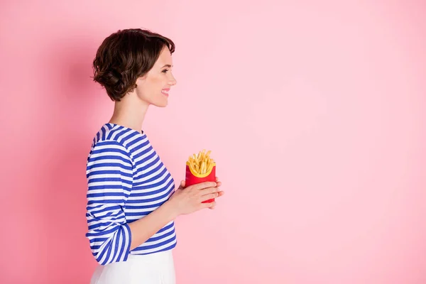 Adatlap side photo of young beautiful smiling cheerful girl look copyspace hold french fries isolated on pink color background — Stock Fotó