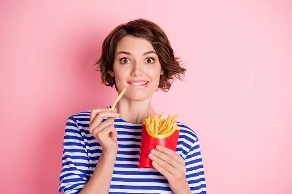 Portré fiatal gyönyörű izgatott őrült éhes csinos lány harapás ajak enni sült krumpli elszigetelt rózsaszín szín háttér — Stock Fotó