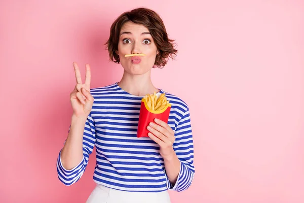 Foto av unga attraktiva funky lura serietjej visar v-tecken pout läppar hålla pommes frites isolerade på rosa färg bakgrund — Stockfoto