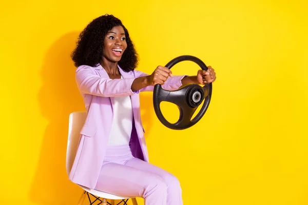 Foto de jovens feliz animado louco sorrindo afro empresária montando carro segurar volante isolado no fundo de cor amarela — Fotografia de Stock