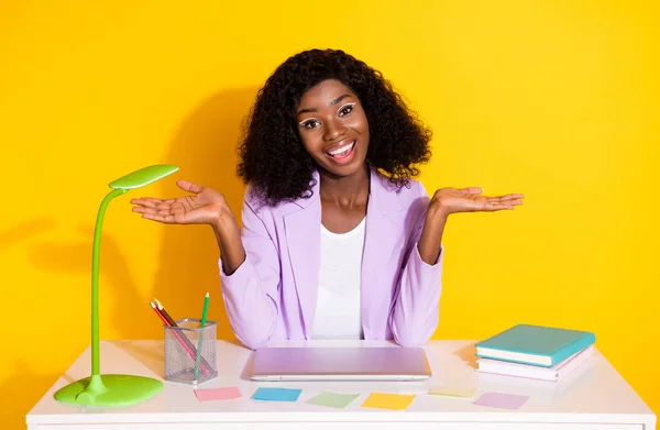 Photo of young happy smiling excited afro woman sit table hold hand in balance advertise isolated on yellow color background — ストック写真