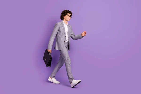 Foto di bello allievo fiducioso ragazzo camminare spostare portare caso indossare vestito grigio calzature isolato colore viola sfondo — Foto Stock