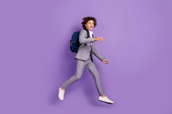 Hoş, aktif, aktif bir öğrencinin fotoğrafı. Atlama hareketi. Sırt çantası, gri ayakkabılar, izole menekşe rengi. — Stok fotoğraf