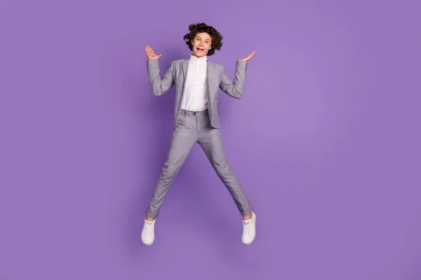 Foto di divertente eccitato pazzo ragazzo salto alzare palme indossare vestito grigio calzature isolato colore viola sfondo — Foto Stock