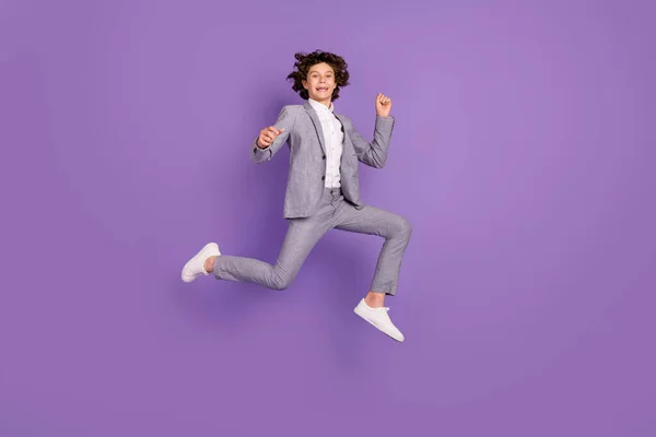 Foto di attivo energico ragazzo salto run godere week-end usura grigio vestito sneakers isolato viola colore sfondo — Foto Stock