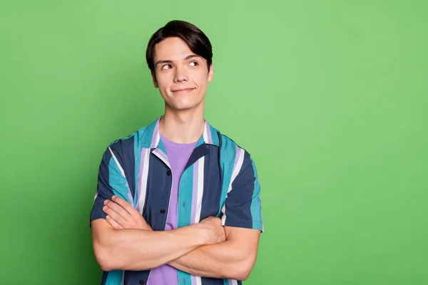 Photo of young happy dreamy man good mood smile look empty space hands crossed isolated on green color background — Zdjęcie stockowe