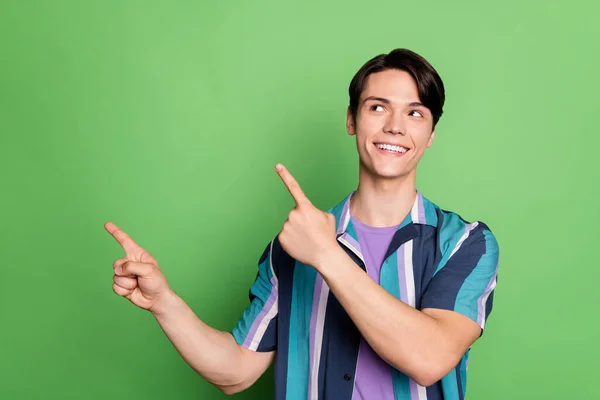 Foto av glada unga glada positiva mannen ser pekfingret tomt utrymme leende isolerad på grön färg bakgrund — Stockfoto