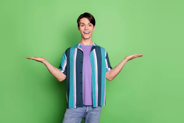 Foto de homem feliz feliz feliz espantado mantenha as mãos vazias escalas de espaço isolado no fundo de cor verde — Fotografia de Stock