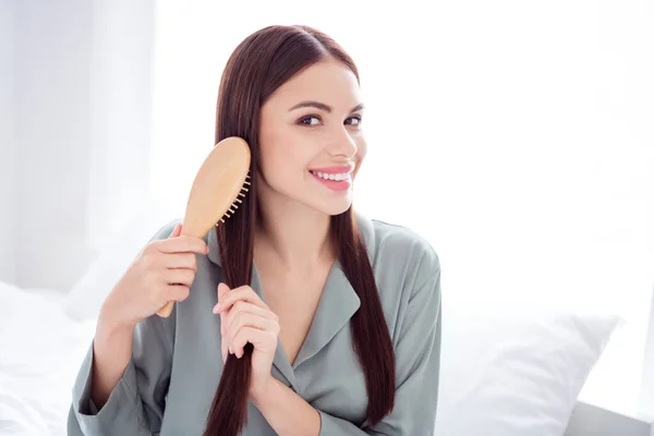 Portrait photo woman sitting on bed in the morning brushing hair — ストック写真