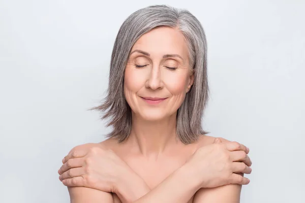 Photo of joyful lovely old woman hug herself closed eyes skin body care isolated on grey color background — Stock Photo, Image