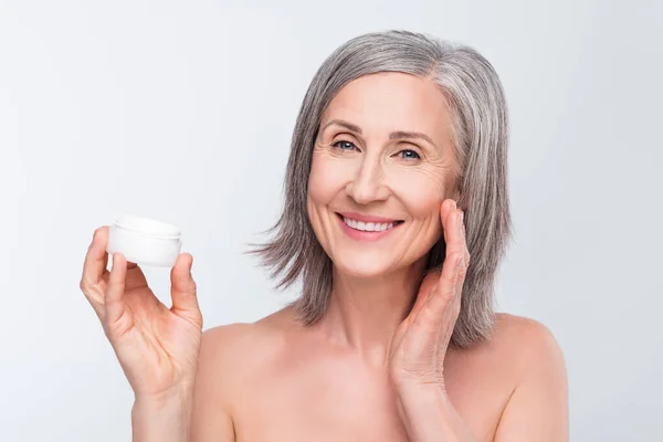 Portrait of attractive nude cheerful woman applying daily cream flawless skin hygiene isolated over gray pastel color background — ストック写真