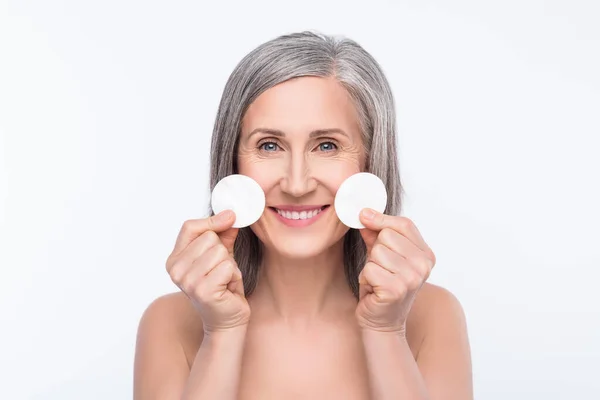 Photo of positive nice old woman hold cotton pads smile good mood skin care isolated on grey color background — ストック写真