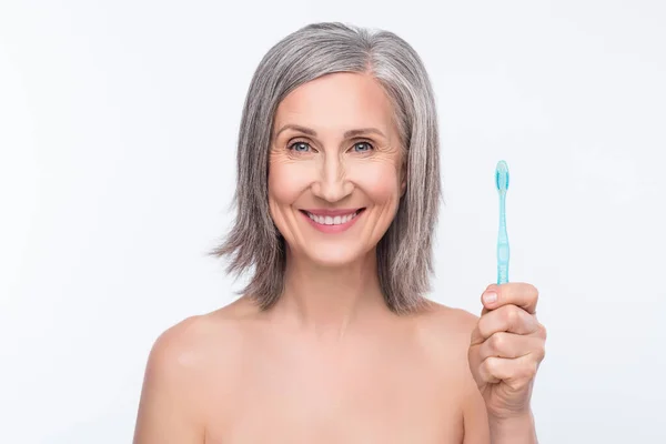 Mutlu, beyaz saçlı, neşeli, yaşlı bir kadının fotoğrafı. Diş fırçası gülüşü, hijyen, gri arka planda izole edilmiş. — Stok fotoğraf