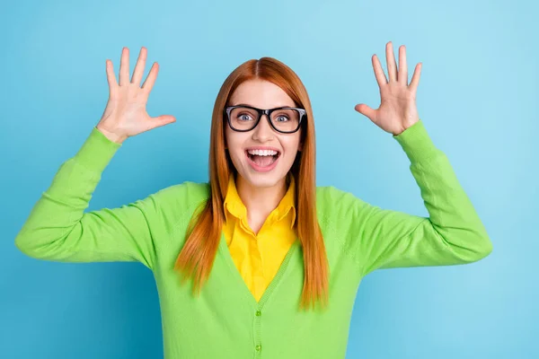 Foto de gengibre espantado penteado jovem senhora braços para cima desgaste óculos verde camisola amarela isolado no fundo de cor azul — Fotografia de Stock