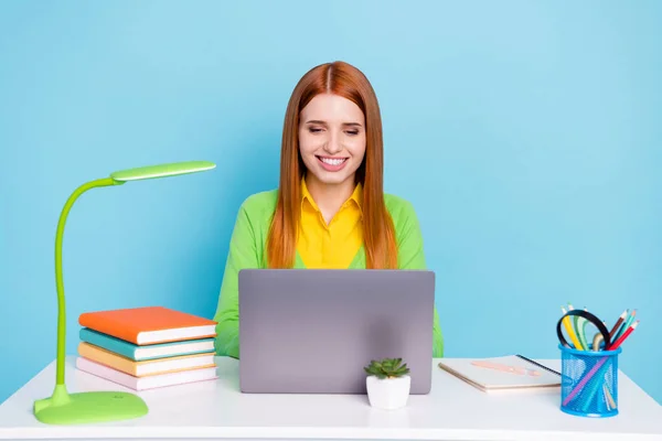 Портрет привабливої зосередженої веселої дівчини з використанням ноутбука робить домашнє завдання ізольовано на пастельному синьому кольоровому фоні — стокове фото