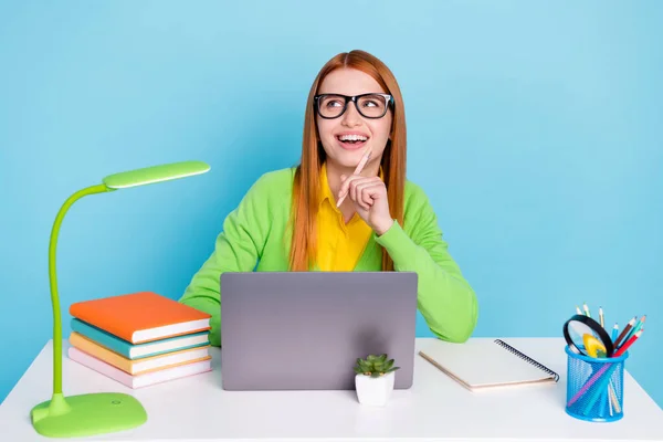 Foto von jungen lustigen roten Frisur Dame halten Stift suchen leeren Raum tragen Brille grünen Pullover isoliert auf blauem Hintergrund — Stockfoto