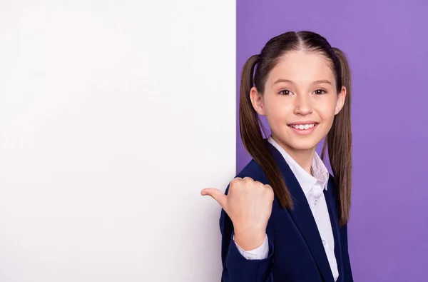Φωτογραφία από γλυκό γοητευτικό κορίτσι σχολείο φορούν μπλε στολή δείχνοντας αντίχειρα λευκό πινακίδα κενό χώρο απομονωμένο πορφυρό φόντο χρώμα — Φωτογραφία Αρχείου