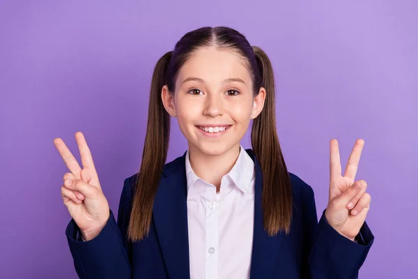 Foto de divertida adorable chica de la escuela usar uniforme azul mostrando signos de v sonriendo aislado color púrpura fondo —  Fotos de Stock