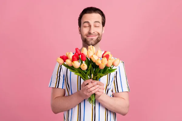 Photo of dreamy young happy charming man smell flowers good mood smile isolated on pastel pink color background — Stockfoto