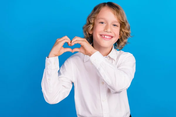 Retrato de menino alegre atraente mostrando símbolo do coração amour cupido isolado sobre fundo de cor azul brilhante — Fotografia de Stock