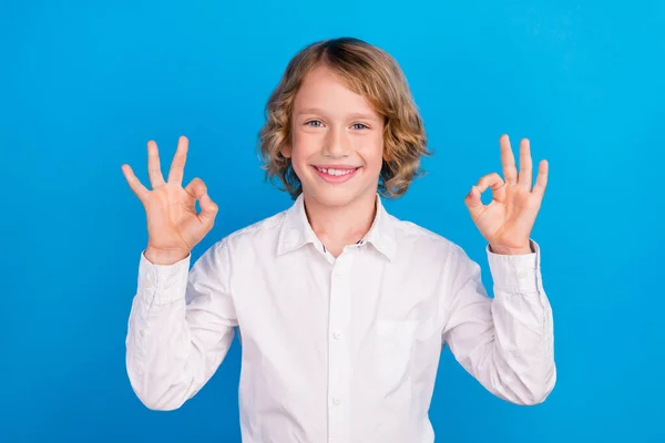 Porträt des attraktiven fröhlichen Jungen zeigt doppelte ok-sign Anzeigenlösung isoliert über hellblauem Hintergrund — Stockfoto