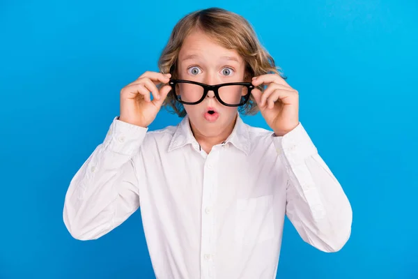 Portrait of attractive amazed boy touching specs pout lips incredible news isolated over vibrant blue color background — Stockfoto