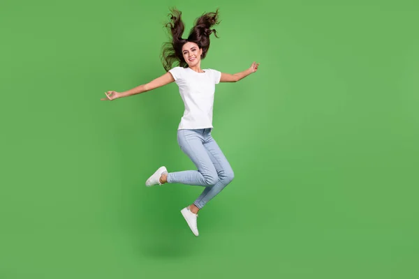 Full längd foto av galen brunett tusenårig dam hoppa slitage t-shirt jeans isolerad på grön färg bakgrund — Stockfoto