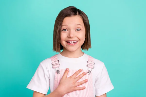 Φωτογραφία του funky ευτυχισμένη μικρό κορίτσι κρατήστε το χέρι στήθος καλή διάθεση ευγνώμων απομονωμένη σε teal φόντο χρώμα — Φωτογραφία Αρχείου